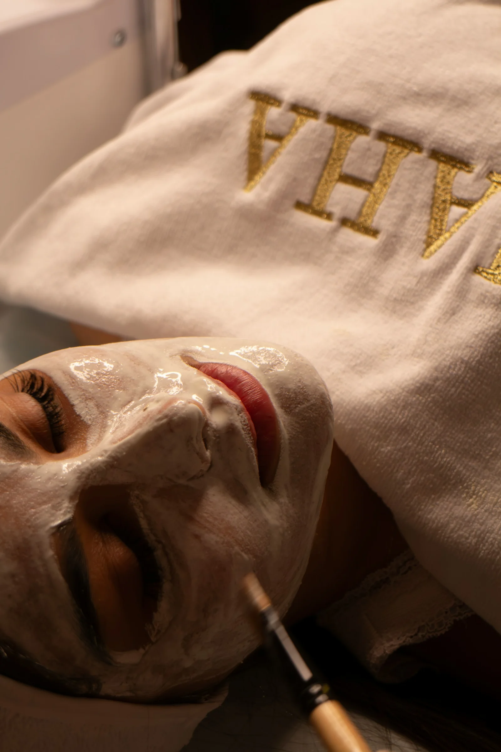 Client relaxing under a towel with a hydrating clay mask